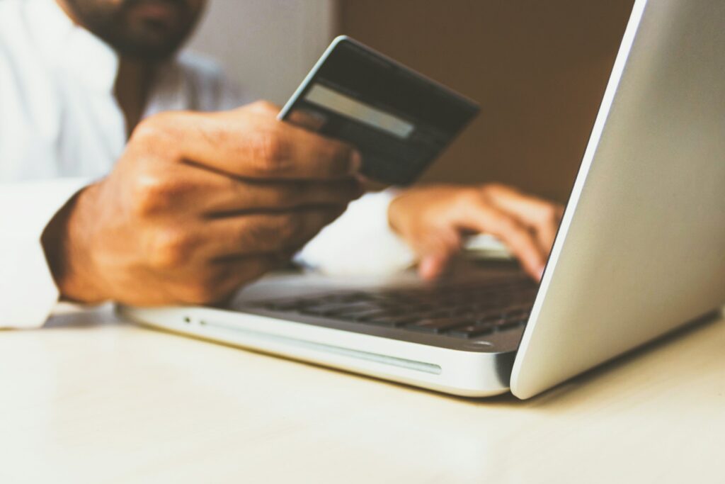 Person bezahlt online mit Kreditkarte am Laptop