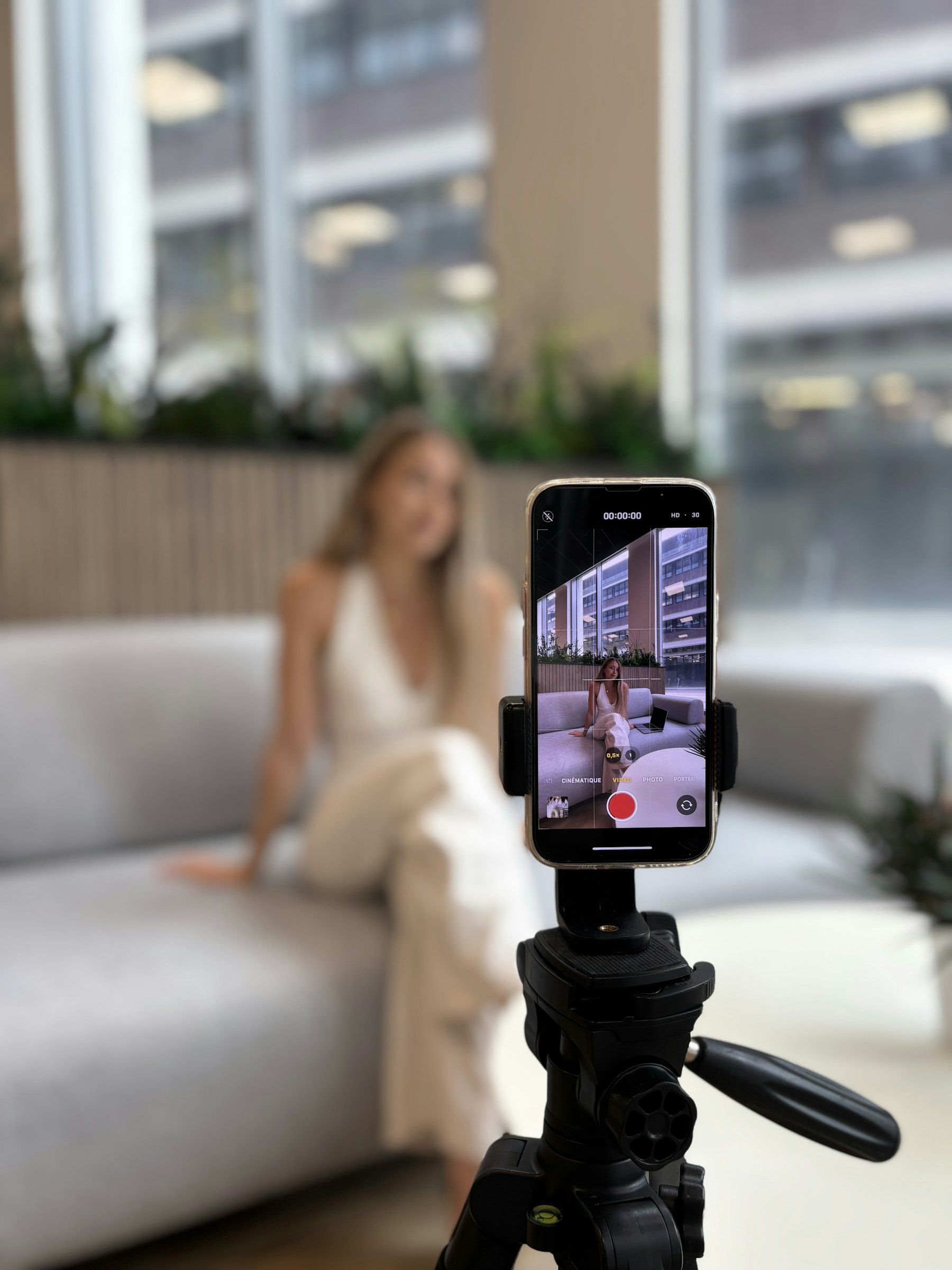 Frau filmt sich selbst mit einem Smartphone auf einem Stativ